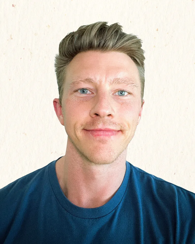 Sean Winslow, photographed against warm paper, head and shoulders bust, light blue eye contact, subtle warm smile.